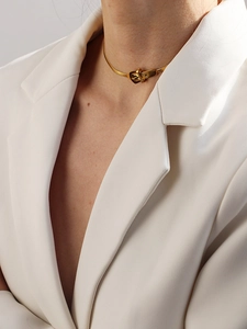 Dettaglio di una collana a serpente dorata con un ciondolo a forma di fibbia di cintura