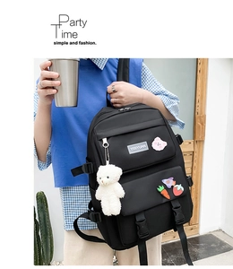 Detail of black nylon school backpack with cute cartoon pins and a plush bear pendant