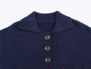 Detailed close-up of dark blue knit polo collar with three brown buttons for women