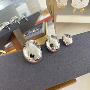 Detailed view of silver oval stud earrings in three sizes on a grey velvet display