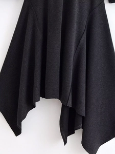 Detail shot of the black asymmetrical hem and textured knit fabric of this stylish dress