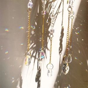 Hanging crystal suncatcher chain with metal rings reflecting rainbow light on wall