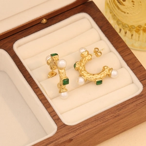 Retro C-shaped gold earrings with white pearls and green gemstones on display