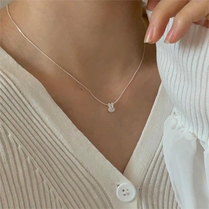 Close-up of minimalist 925 silver rabbit necklace with shiny diamonds on female model