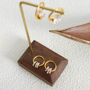Elegante vergoldete Creolen mit kleinen Kristallen auf einem Schmuckständer aus Holz