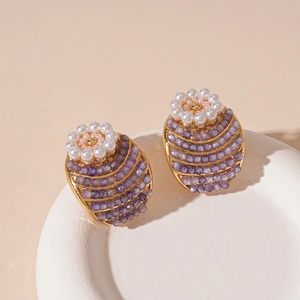 Detail of vintage flower earrings with pearls and purple beads on a white tray