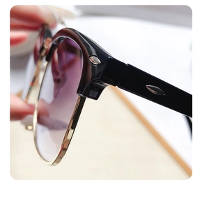 Detailed close-up of retro semi-rimless sunglasses with gold metal trim and purple gradient lens