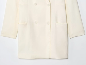 Detail of cream double-breasted blazer with four tonal buttons and side flat pockets