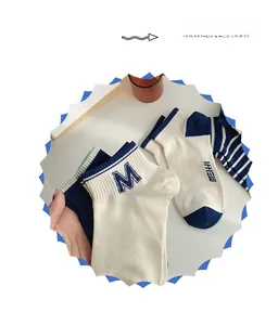Detail view of cotton socks featuring navy blue stripes and embroidered M and NEW lettering