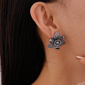 Close-up of vintage gunmetal flower earrings with deep purple zircons worn by a model