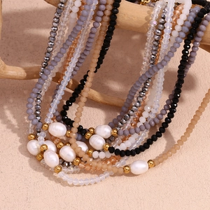 Multilayer beaded necklace with freshwater pearls and faceted crystals on a wooden stand
