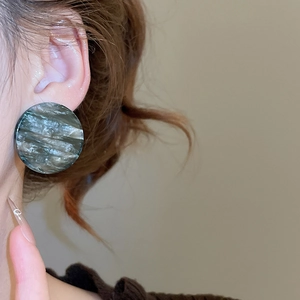 Gros plan d'une boucle d'oreille ronde en acrylique marbré portée par un mannequin
