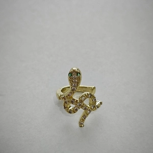 Macro detail of snake-shaped golden ear cuff featuring green gem eyes and sparkling crystals