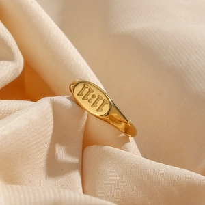 Close-up of 18K gold plated oval ring with 11:11 engraving on beige silk fabric