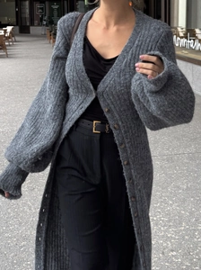 Détail d'un long gilet en grosse maille gris foncé avec manches lanternes et boutons