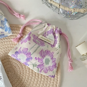 Gros plan d'un petit sac à cordon en toile fleurie sur un dessous-de-verre