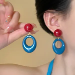 Close-up of a model wearing retro red and blue contrast resin hoop earrings