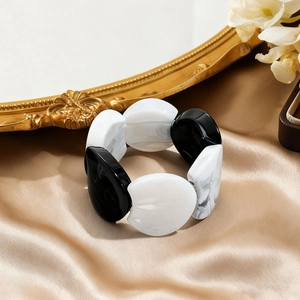 Detail of retro acrylic bangle with black and white marble pattern on champagne silk
