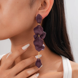 Close-up of deep purple acrylic petal drop earrings with gold chain on model