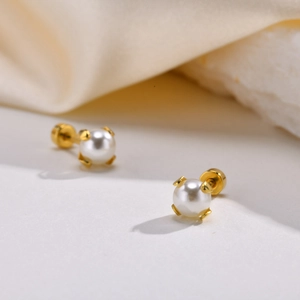 Detail of white round pearl earrings with gold screw back and four-claw setting