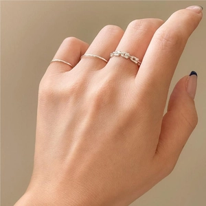 Detail of minimalist 925 sterling silver anchor chain rings worn on a female hand