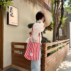 Detail of red and white striped canvas tote bag with lace trim on a model outdoors