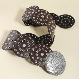Detail of dark brown leather discs with silver metal eyelets and decorative carved buckle