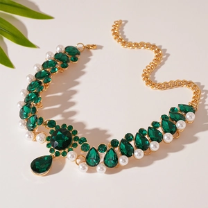 Detail of vintage necklace with emerald green crystals and white pearls on gold base