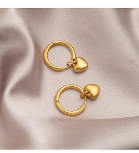Detail of heart-shaped gold titanium earrings on purple silk background fabric
