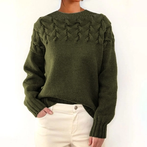 Detail of dark green cable knit sweater featuring thick textured geometric patterns