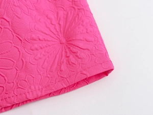 Close-up of pink embossed floral fabric with high relief texture on a mini dress