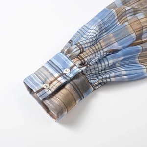 Detail of plaid shirt cuff with blue patterns, gold threads and two white buttons