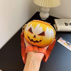 Close-up of Halloween pumpkin crossbody bag with wide patterned strap and smiling face detail