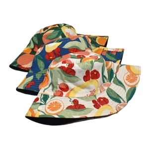 Reversible bucket hats with tropical fruit prints in white, navy, and dark green colors