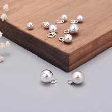 Close-up of S925 sterling silver ball charms with hanging rings on wood surface
