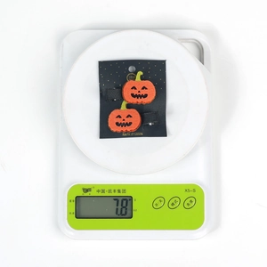 Detail shot of a pair of orange felt pumpkin hair clips on a scale showing 7.8g weight