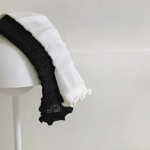 Close-up of black and white lace mesh socks with ruffled edges on a white lamp