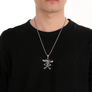 Close-up of a silver skull and crossbones pendant on a woven chain worn by a male model