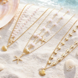 Collana dorata stile oceano con ciondoli a stella marina e conchiglia sulla spiaggia