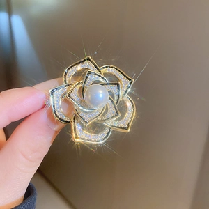 Détail de la broche camélia dorée avec pétales en zircon et une grande perle ronde