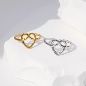 Detail showing gold and silver heart knot rings displayed on minimalist stone blocks