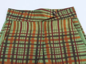 Dettaglio dei pantaloni a quadri con chiusura a bottone singolo e cuciture in vita