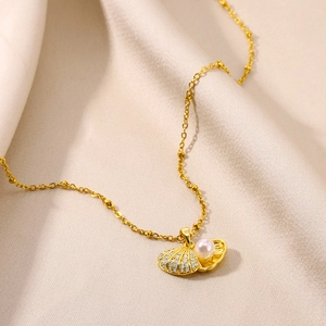 Detail of gold shell pendant necklace with white pearl and sparkling crystals