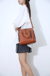 Close-up of brown woven texture handbag with fringe tassel and adjustable shoulder strap