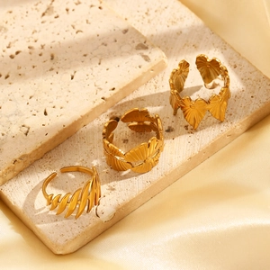 Close-up of three gold adjustable rings with leaf textures on a stone surface