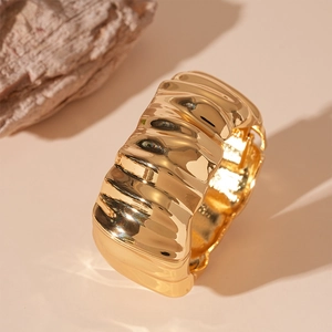 Detail showing wide gold pleated metal cuff bracelet with unique wrinkled texture finish