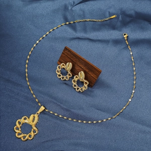 Macro shot of gold-plated knot jewelry set with necklace and earrings on blue satin