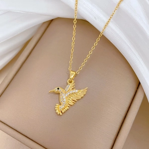 Detail of a gold hummingbird pendant necklace with sparkling pavé crystals on a jewelry box