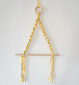 Detail of yellow macrame tissue holder with wooden ring and hand-woven cotton rope