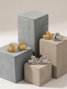 Detailed view of heart-shaped earrings with hammered texture in gold and silver finish